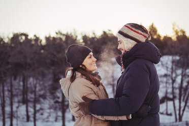 Happy couple embracing on field during winter - MASF03530