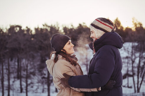 Happy couple embracing on field during winter - MASF03530