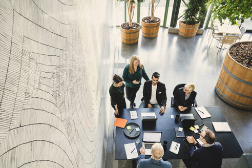 High angle view of multi-ethnic business people discussing at table in office - MASF03546