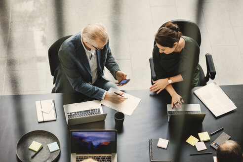 High angle view of businessman and businesswoman discussing at table in office - MASF03549