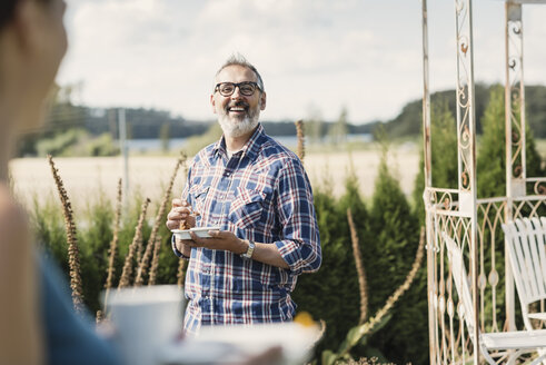 Happy mature man smiling at female friend in back yard - MASF03553