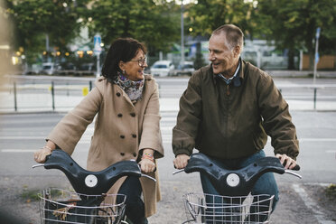 Glückliches älteres Paar nimmt Leihfahrräder auf einem Parkplatz entgegen - MASF03559