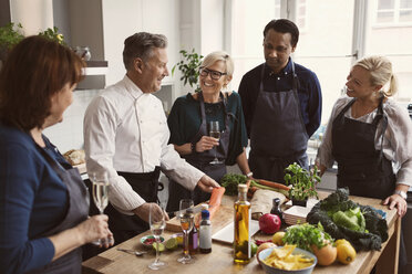 Happy chef preparing food while teaching to students standing at table - MASF03581