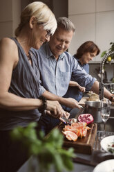 Glückliche Freunde bereiten in der Küche Essen zu - MASF03584