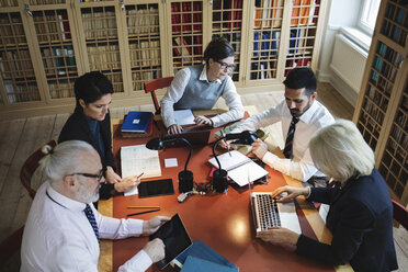 Hochformatige Ansicht von Fachleuten, die an einem Tisch in einer juristischen Bibliothek arbeiten - MASF03592