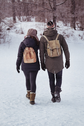 Rückansicht eines Paares in voller Länge auf einem verschneiten Feld, lizenzfreies Stockfoto