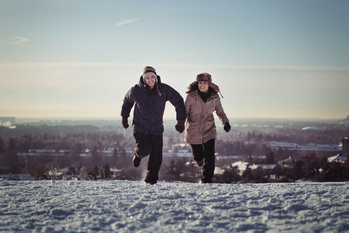 Full length of happy couple running on snow covered mountains - MASF03606