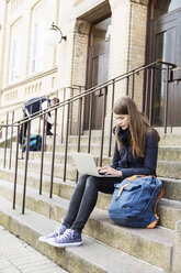 Junge Frau benutzt Laptop auf den Stufen einer High School - MASF03675
