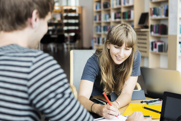 Junge Frau mit männlichem Freund studiert zusammen in der Universitätsbibliothek - MASF03680