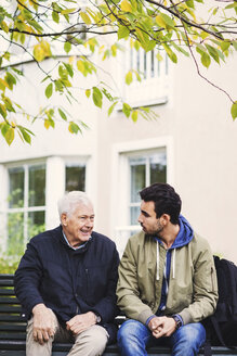 Hausmeister unterhält sich mit einem älteren Mann, der auf einer Bank sitzt - MASF03687