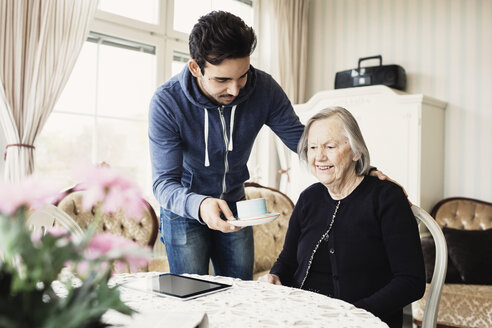 Hausmeister serviert einer älteren Frau im Pflegeheim Kaffee - MASF03690