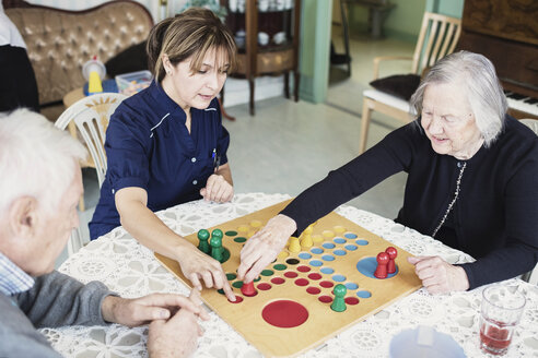 Hausmeister spielt Ludo mit Senioren im Pflegeheim - MASF03694