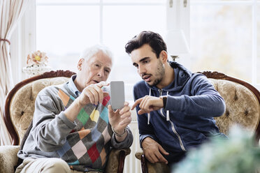 Hausmeister hilft älterem Mann bei der Benutzung eines Mobiltelefons im Pflegeheim - MASF03695