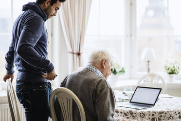 Hausmeister und älterer Mann mit Laptop am Esstisch - MASF03696