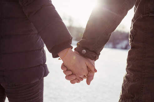 Cropped image male and female hiker holding hands during winter - MASF03701