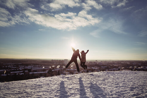 Couple jumping on snow covered mountains against sky - MASF03706