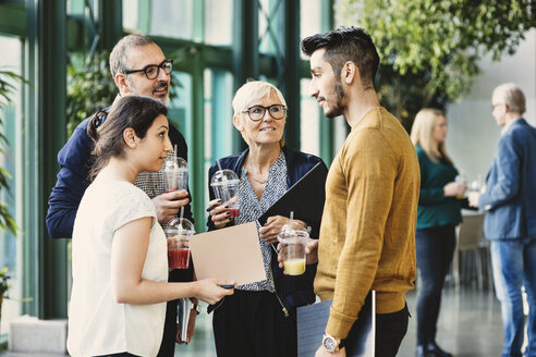 Creative business people discussing while having juice in office - MASF03724