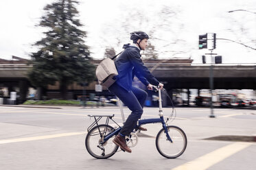 Seitenansicht eines Geschäftsmannes, der auf einer Straße Fahrrad fährt - CAVF38040