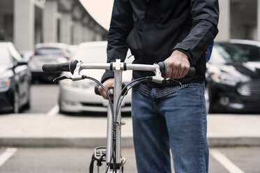 Midsection of businessman holding bicycle on city street - CAVF38045