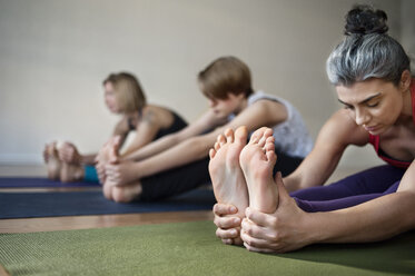 Frau berührt Füße beim Yoga im Fitnessstudio - CAVF38060