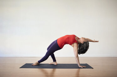 Frau führt Balance-Yoga-Übung im Fitnessstudio durch - CAVF38063