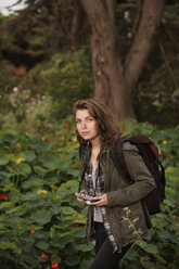 Porträt einer schönen Wanderin mit Kamera im Wald - CAVF38100