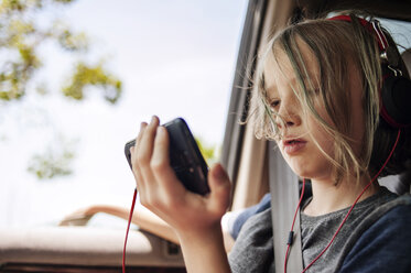 Junge hört mit seinem Handy Musik, während er im Auto sitzt - CAVF38118