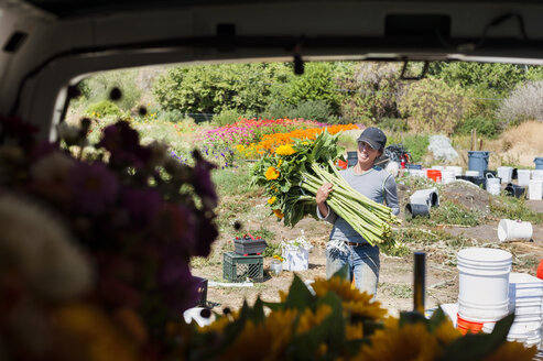 Porträt einer Frau, die einen Blumenstrauß trägt, gesehen durch die hintere Windschutzscheibe - CAVF38168