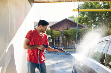 Mann wäscht Auto in Garage an sonnigem Tag - CAVF38190