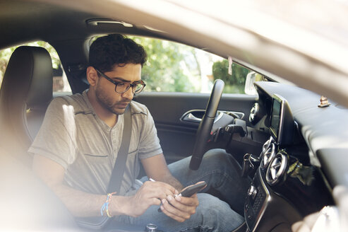 Mann benutzt Mobiltelefon, während er im Auto sitzt - CAVF38195