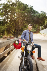 Portrait of handsome man sitting on motorcycle - CAVF38201