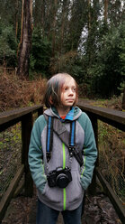 Junge mit Kamera am Zaun im Wald stehend - CAVF38210