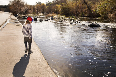 Rear view of boy walking at riverbank - CAVF38236