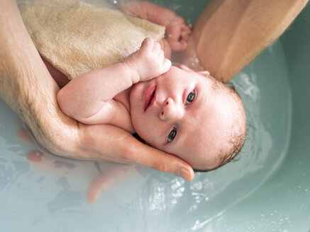 Mann badet neugeborenes Mädchen in einer Wanne - LAF01995