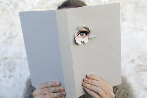 Frau bedeckt Gesicht mit Buch, liest Gedichte, Auge schaut durch den Einband - PSTF00107