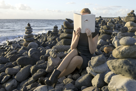 Frau bedeckt Gesicht mit Buch, liest Gedichte, Auge schaut durch den Einband, lizenzfreies Stockfoto