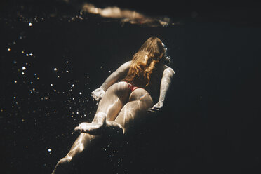 Rear view of woman swimming underwater - CAVF38264