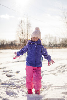 Porträt eines Mädchens, das auf einem verschneiten Feld vor dem Himmel steht - CAVF38289