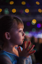 Close-up of thoughtful girl against defocused lights at night - CAVF38291