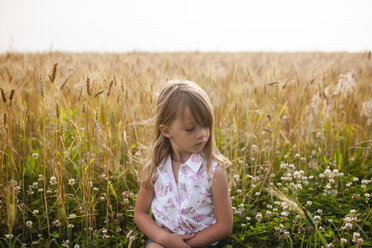 Upset girl sitting on field against sky in farm - CAVF38296