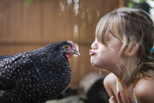 Happy girl puckering hen outdoors - CAVF38307