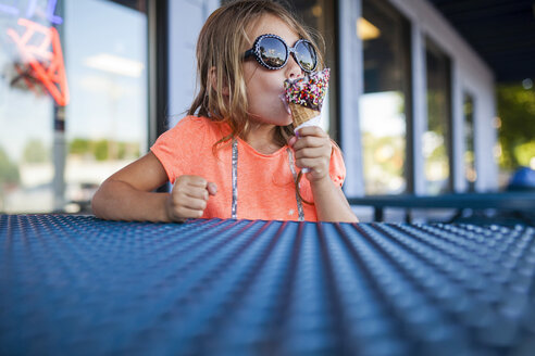 Mädchen mit Sonnenbrille isst Eis im Eiscafé - CAVF38363