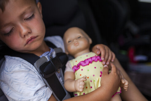 Junge schläft mit Puppe im Auto - CAVF38364