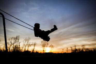 Silhouette girl playing on swing against sky during sunset - CAVF38373