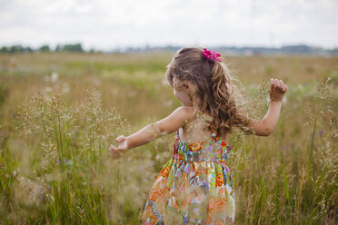 Girl with arms outstretched playing on grassy field - CAVF38377