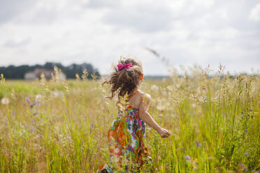 Rückansicht eines Mädchens beim Laufen auf einer Wiese gegen den Himmel - CAVF38378