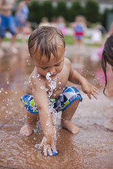 Niedlicher Junge spielt mit Ball auf Wasserbrunnen - CAVF38379