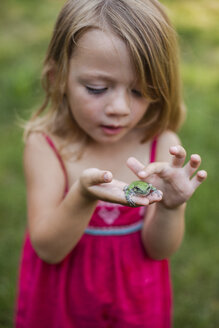Nettes Mädchen spielt mit Frosch im Garten - CAVF38382