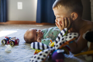 Baby-Mädchen schaut Bruder an, während sie auf dem Bett liegt - CAVF38394