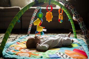 Babymädchen auf Spielmatte zu Hause liegend - CAVF38397